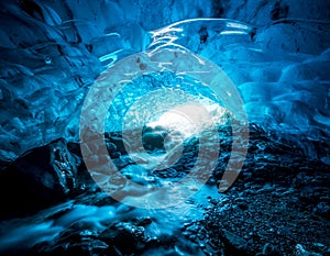 Entrance of an crystal blue ice cave with underground river inside, Vatnajokull glacier, Iceland