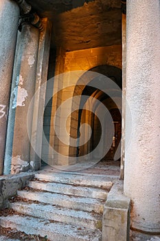 Entrance door of a decayed building with classic columns, stairs and arcade