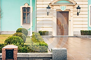 Entrance door on facade of an old blue baroque building with lawn, decorative tree and boxwood bushes, Mariinsky Palace in Kiev,