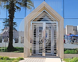 Entrance door to a public building in the mirror wall, made in modern style from nickel-coated steel with glass filling