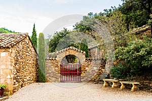 Entrance at Fontfroide Abbey monastery in France. Red gate and stone bench