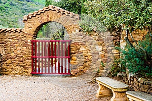 Entrance at Fontfroide Abbey monastery in France. Red gate and stone bench