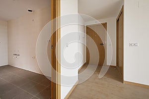 Entrance hall of an empty house with an oak wood access door to match the rest of the doors, a built-in wardrobe with sliding