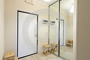 Entrance hall interior with metal front door and large sliding wardrobe with mirrors