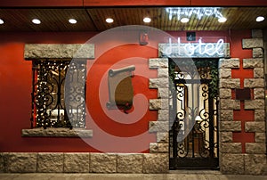 Entrance of a hotel with luminous neon. Red wall.