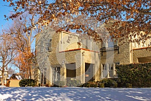 Entrance of landscaped stucco two story house with snow on the ground in upscale neighborhood