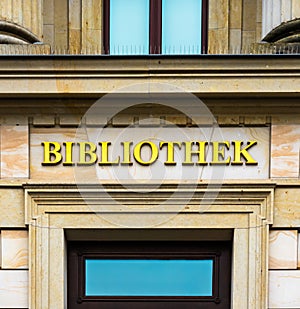 Entrance of a library in an ancient building labelled with golden letters