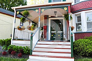 Entrance of old ornate gingerbread victorian style house decorated for summer with flowers and porch decor