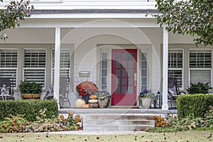 Entrance and porch to pretty house with Autumn and Halloween decorations and fall leaves blowing in the wind - curb appeal