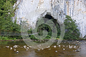 The entrance portal of Unguru Mare cave, the access suspended bridge and Crisul Repede river. Apuseni Mountains, Romania. photo