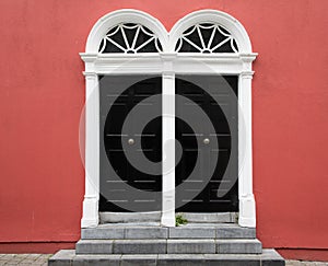 Entrance of Red Building with Stone Steps and Pair of Black Doors with Fan Transoms