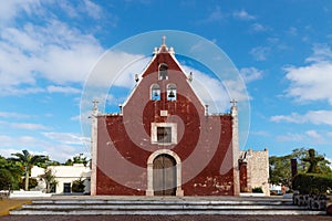 Entrance of the red colonial church Itzimna in a park with trees, Merida, Yucatan, Mexico photo