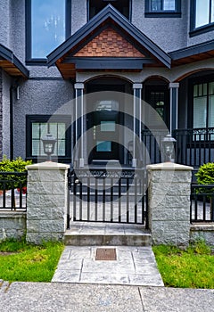 Entrance of residential house with metal grid gate in front. Dark colored house with entrance gate