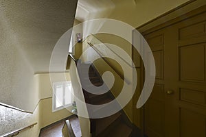 Entrance of a residential house with a solid wooden door and stairs between the floors