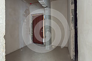 The entrance to apartment is a new building, the front door and bare concrete and plastered walls