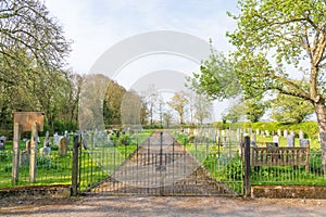 Entrance to cemetery showing front gates with park bench and trees. Hertfordshire. UK