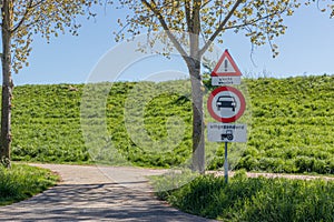 Entrance to a country path with traffic signs: a prohibited cars, caution triangle, signs: bad road and except tractor