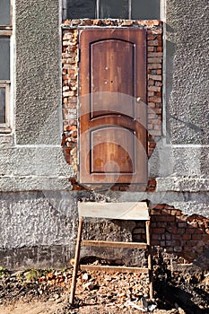 Entrance to destroyed building, wooden door, metal staircase, wi