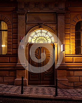 Entrance to a grand building with arched doorways illuminated at night in Prague, Czech Republic