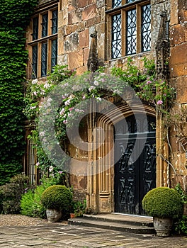 Entrance to a historic manor, framed by antique architectural elements and flanked by potted topiaries, features an aged photo