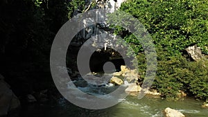 The entrance to Konglor cave hidden by rocks and tropical vegetation