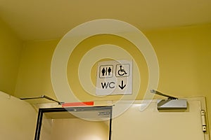 An entrance to the male, female and disabled toilet. wc symbol on yellow wall