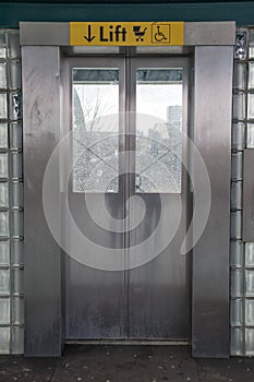 Entrance to modern lift with sign above the doors for pram and disabled use