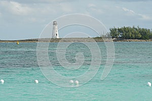 Entrance to Nassau harbour in the Bahamas with old white lighthouse on a breakwater.