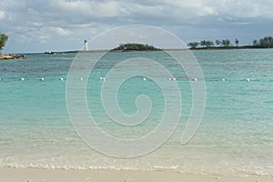 Entrance to Nassau port in the Bahamas with old white lighthouse on a breakwater.