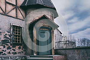 Entrance to the old Catholic Church. Closed door with a cross over the door on a dark sky background, copy space