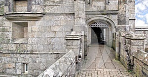 Entrance to an old stone walled castle with portcullis