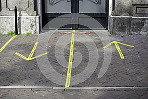 Entrance to a pub with yellow sticker tape reminding people in Dutch to keep social distancing