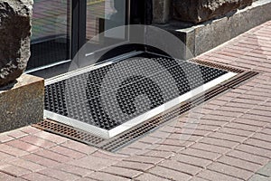 Entrance to the store from a pedestrian sidewalk from a rubber foot mat with storm drain.