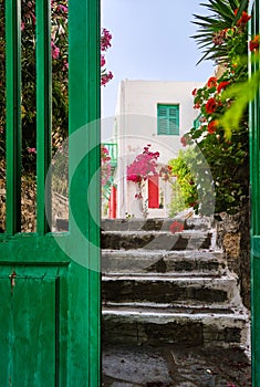 Entrance to traditional Greek island house. Whitewashed walls, pink bougainvillea, red and green storm shutters