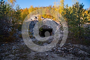 Entrance to the tunnels, old abandoned quarry mines near the city of Sataniv, Ukraine. Autumn day. Stones and wood