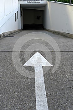 Entrance to an underground parking with a white arrow showing direction.