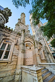 Entrance and tower of Chicago water tower with lush green tree, tourism of city, historic attraction
