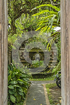 Entrance of an traditional Balinese house with green plants and stone sculptures