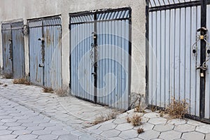 Entrances to parking spaces for cars in the courtyard of an apartment building. Lots of metal garage doors. Garage