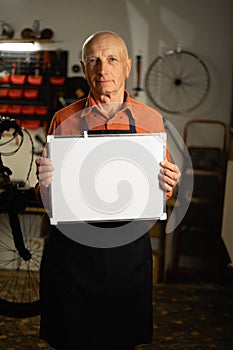 Entrepreneur, bike mechanic, elderly small business owner and retail service expert holding white markerboard standing