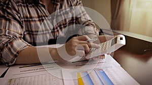 Entrepreneur or Businessman using a calculator with a pen in her hand and calculate financial expense, tax, accounting, statistics