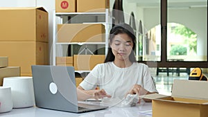 Entrepreneur checks online orders and packs goods for customers in a startup workspace.