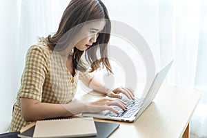 Entrepreneur concept a young female freelancer working on her laptop device typing an urgent document seriously