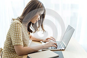 Entrepreneur concept a young female freelancer working on her laptop device typing an urgent document seriously