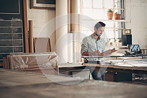Entrepreneur in his workshop checking figures on a clipboard photo