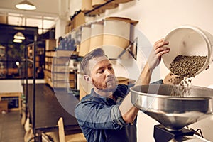 Entrepreneur pouring raw coffee beans into a modern roasting mac