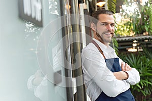 Bearded Man Business Owner with arms crossed standing at front of cafe