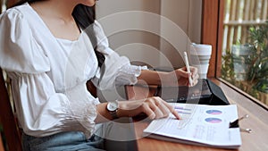 Entrepreneur working at cafe, diligently taking notes on her task using a tablet