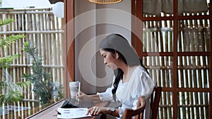 Entrepreneur working at cafe, diligently taking notes on her task using a tablet