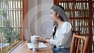 Entrepreneur working at a nearby cafe conversing with colleagues using earphones